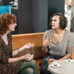 Twee vrouwen zitten op een bank samen te praten.
