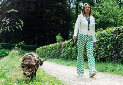 Een vrouw loopt buiten op een pad, met haar bruine hond aan de lijn.