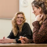 Twee vrouwen zitten pratend naast elkaar.