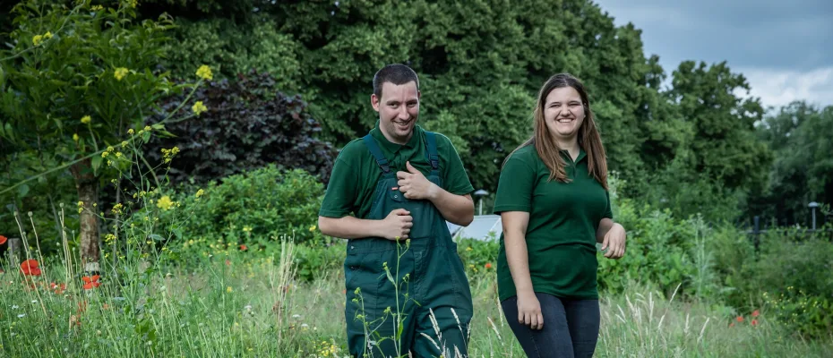 Een man en een vrouw lopen naast elkaar tussen hoge gras.